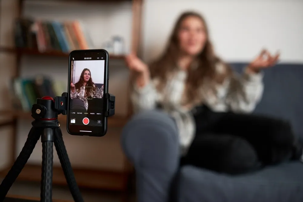 Nagrywanie vloga telefonem: twórczyni contentu mówi do kamery w domowym studio.